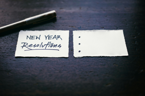 Two small pieces of paper beside each other with one that says "New Year Resolutions" and the other with three bullet points