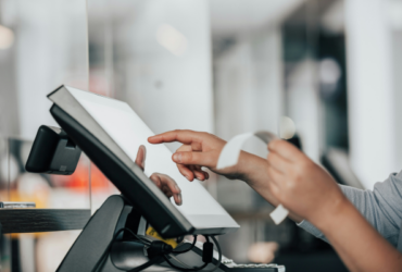 Business owner holding receipt and touching computer screen