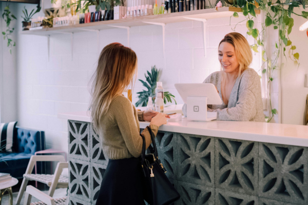 Business owner behind front desk performing a transaction with customer on other side of desk