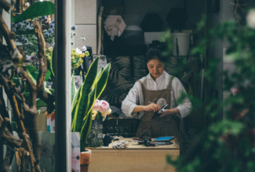 Small business owner, florist, in shoppe surrounded by greenery.