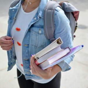 Student wearing a backpack and holding books