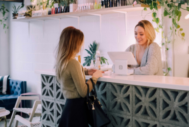 Business owner behind front desk performing a transaction with customer on other side of desk